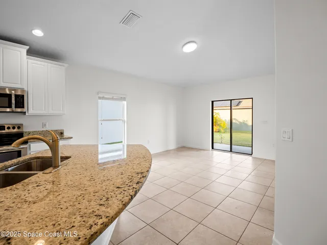 a view of a kitchen with granite countertop a sink and a stove top oven