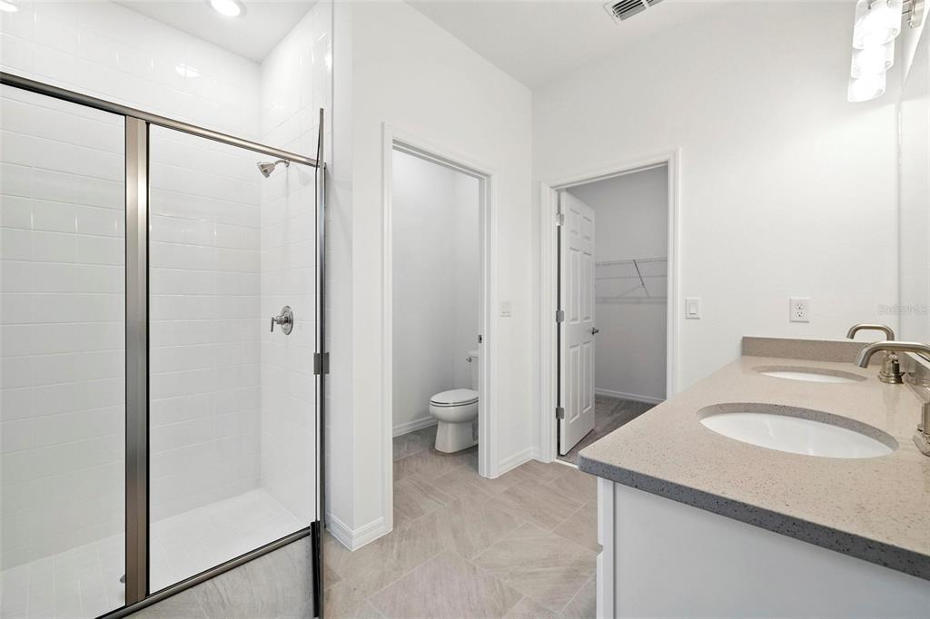 27517 Stellar Sea Way Howey-in-the-Hills, FL 34737 - Photo 11 of 17 a bathroom with a granite countertop sink toilet and shower