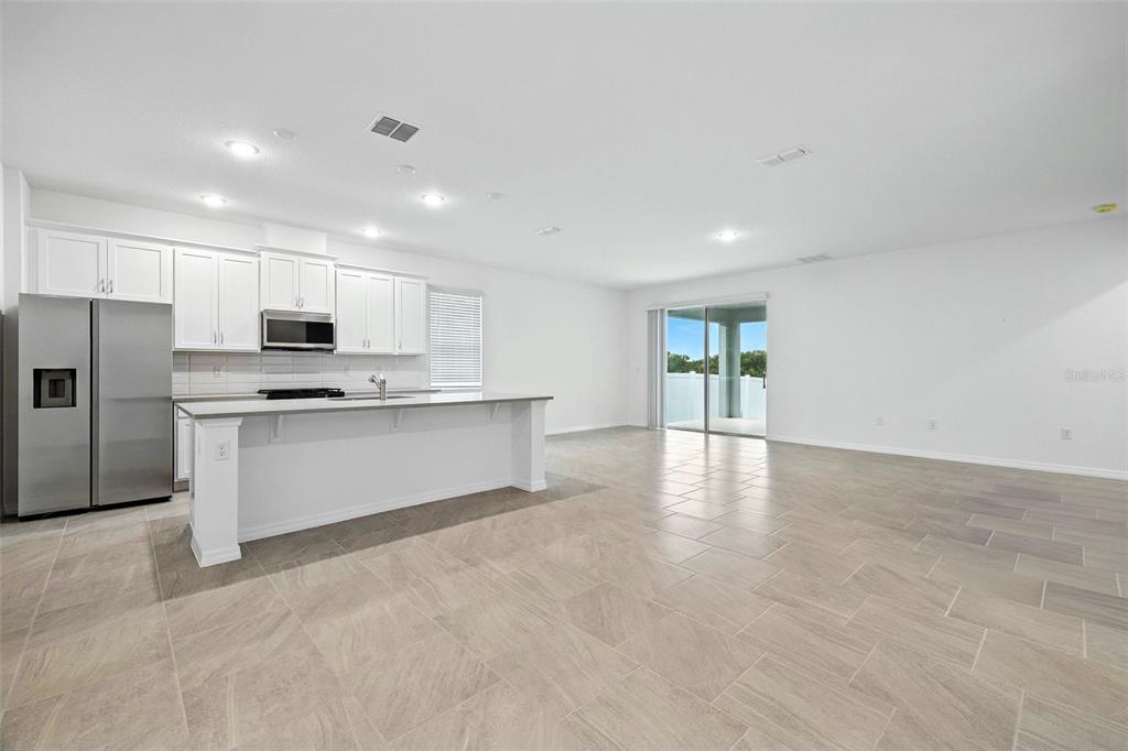 27517 Stellar Sea Way Howey-in-the-Hills, FL 34737 - Photo 5 of 17 a kitchen with stainless steel appliances a refrigerator sink and microwave