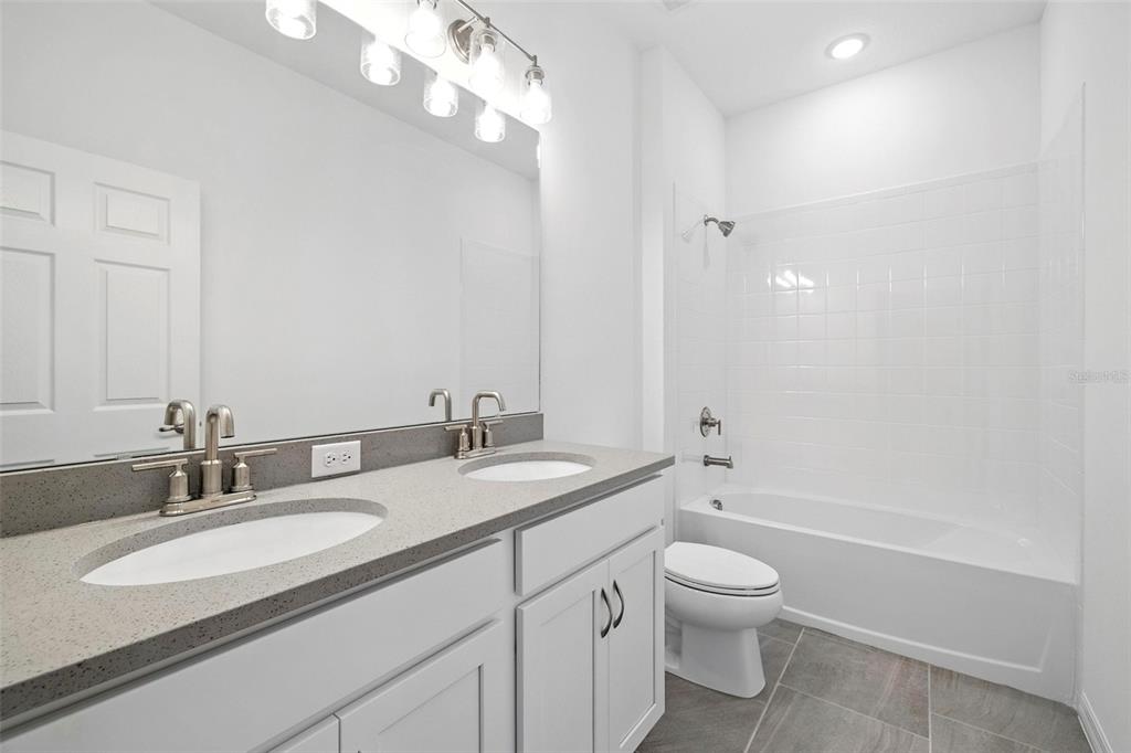 27517 Stellar Sea Way Howey-in-the-Hills, FL 34737 - Photo 6 of 17 a bathroom with a granite countertop toilet a sink and a mirror