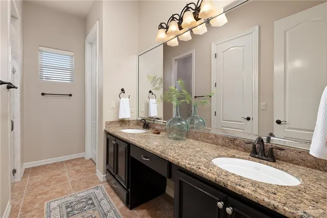 a bathroom with a granite countertop double vanity and a mirror