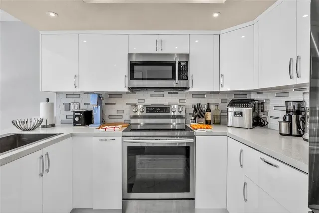 a kitchen with stainless steel appliances granite countertop a stove a sink and a microwave