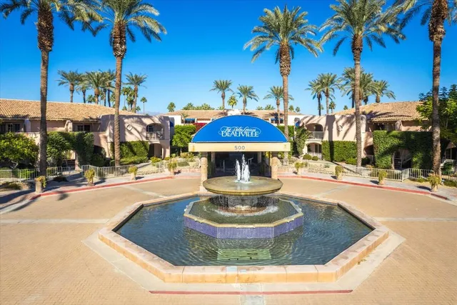 a view of a swimming pool with a lawn chairs and palm trees