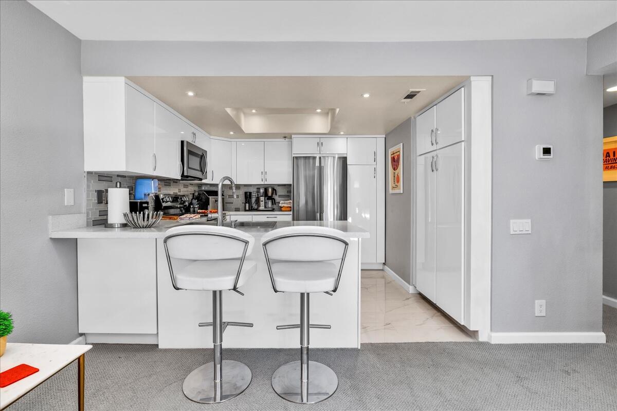 500 East Amado Road, Unit 416 Palm Springs, CA 92262 - Photo 7 of 48 a kitchen with stainless steel appliances kitchen island granite countertop a refrigerator a stove a sink and white cabinets with wooden floor