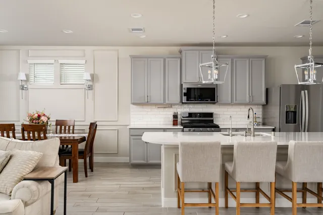 a kitchen with stainless steel appliances granite countertop a dining table chairs refrigerator and microwave