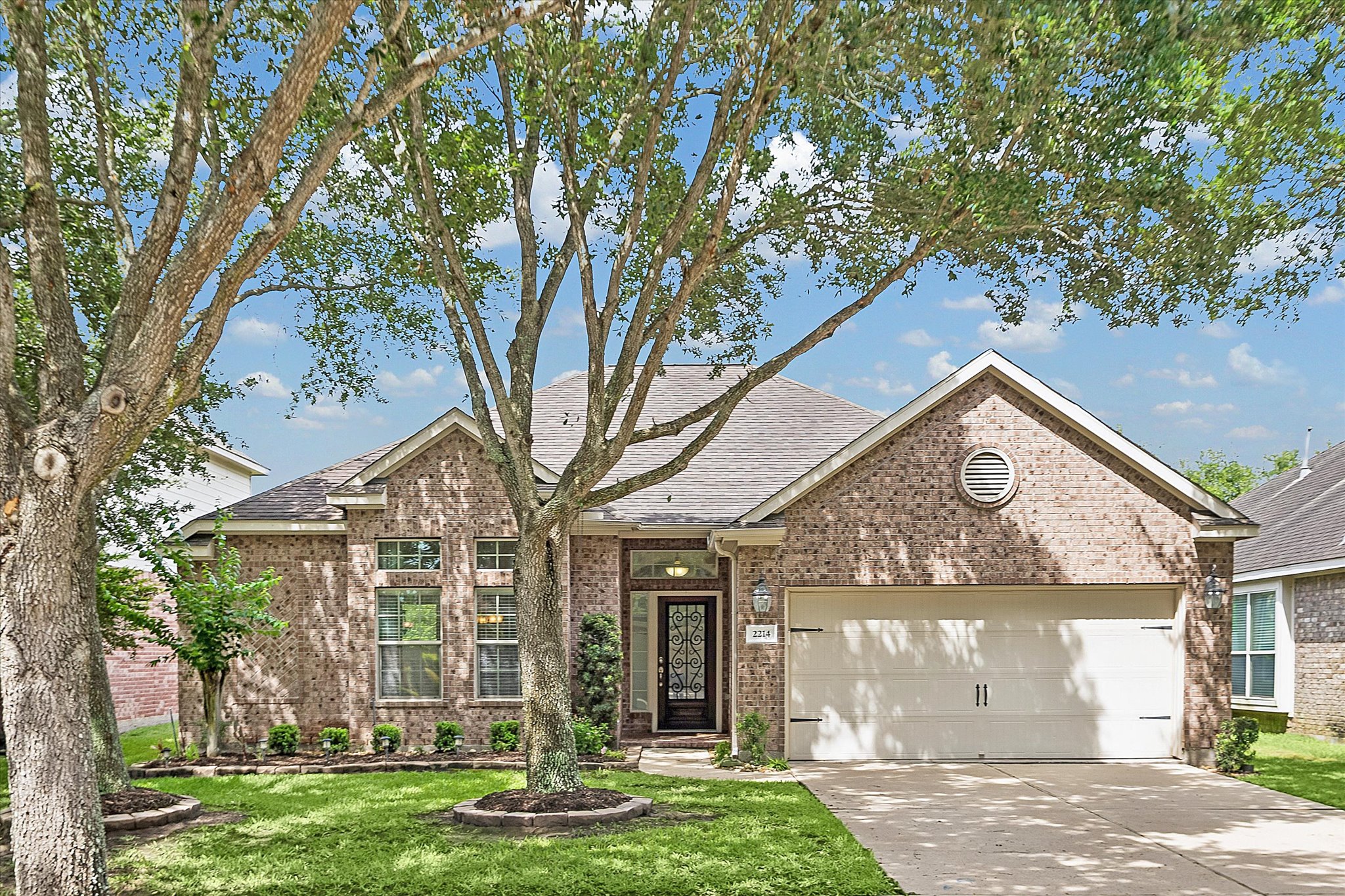 2214 Wembley Way Rosenberg, TX 77471 - Photo 5 of 35 Brick facade residence featuring a two-car garage, mature trees, and landscaping