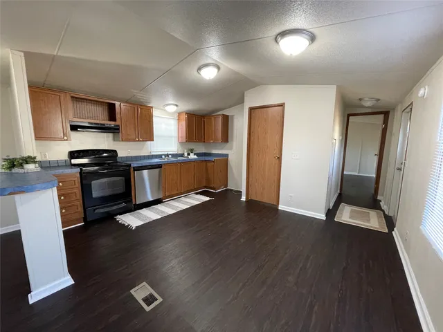a kitchen with stainless steel appliances wooden floors and white cabinets