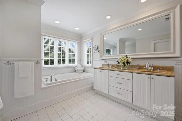 a spacious bathroom with a granite countertop sink a mirror and a bathtub