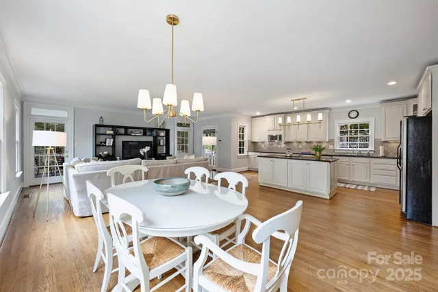 a view of a dining room and livingroom with furniture wooden floor a chandelier