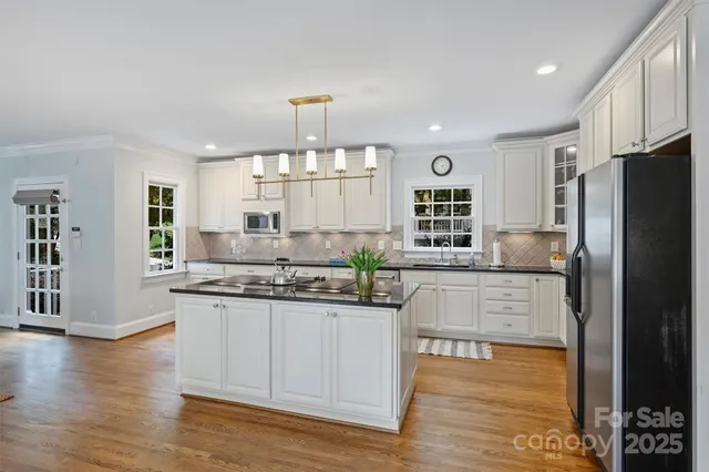 a kitchen with stainless steel appliances granite countertop a refrigerator a stove and a wooden floors