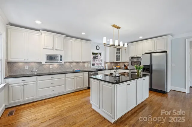 a kitchen with kitchen island granite countertop a sink cabinets and stainless steel appliances
