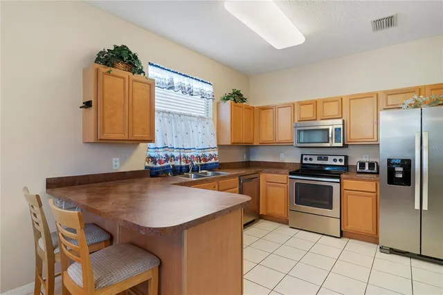 a kitchen with granite countertop stainless steel appliances a stove top oven a sink a dining table and chairs