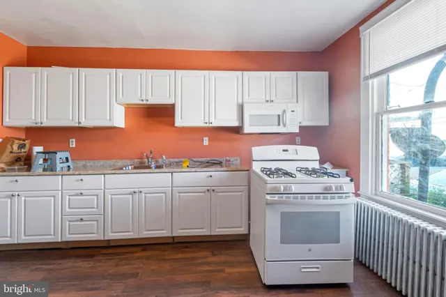 a kitchen with cabinets appliances and wooden floor