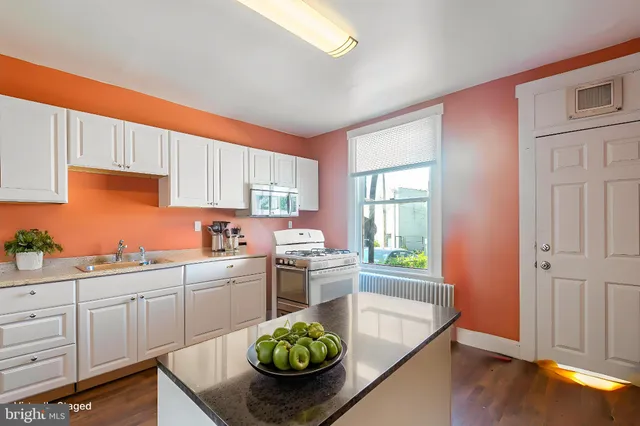 a kitchen with a sink cabinets wooden floor and stainless steel appliances