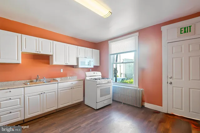 a kitchen with granite countertop a sink a stove cabinets and wooden floor