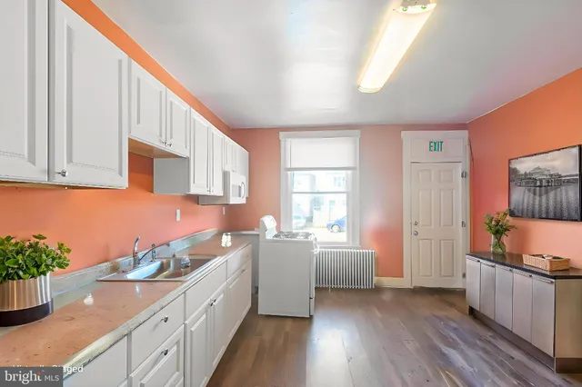 a living room with stainless steel appliances furniture and a kitchen view