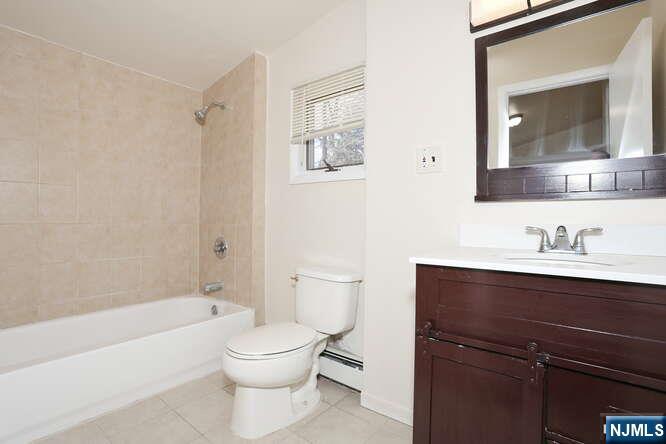 68 Mohawk Avenue, Unit 2 Hawthorne, NJ 07506 - Photo 12 of 24 a bathroom with a toilet a sink a mirror and a bathtub