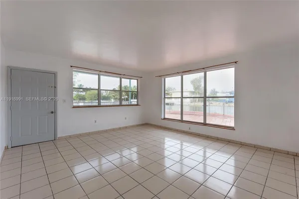 a view of an empty room with window and a kitchen