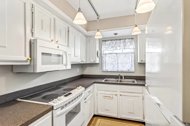 a kitchen with granite countertop white cabinets and window