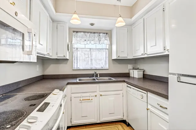 a kitchen with granite countertop a sink stainless steel appliances white cabinets and a window