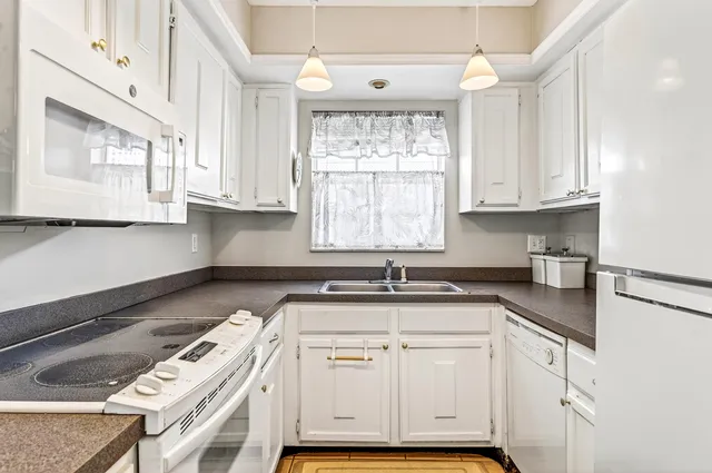 a kitchen with granite countertop a sink a window and cabinets