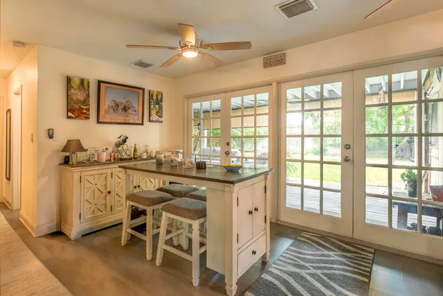 a room with chandelier fan and windows