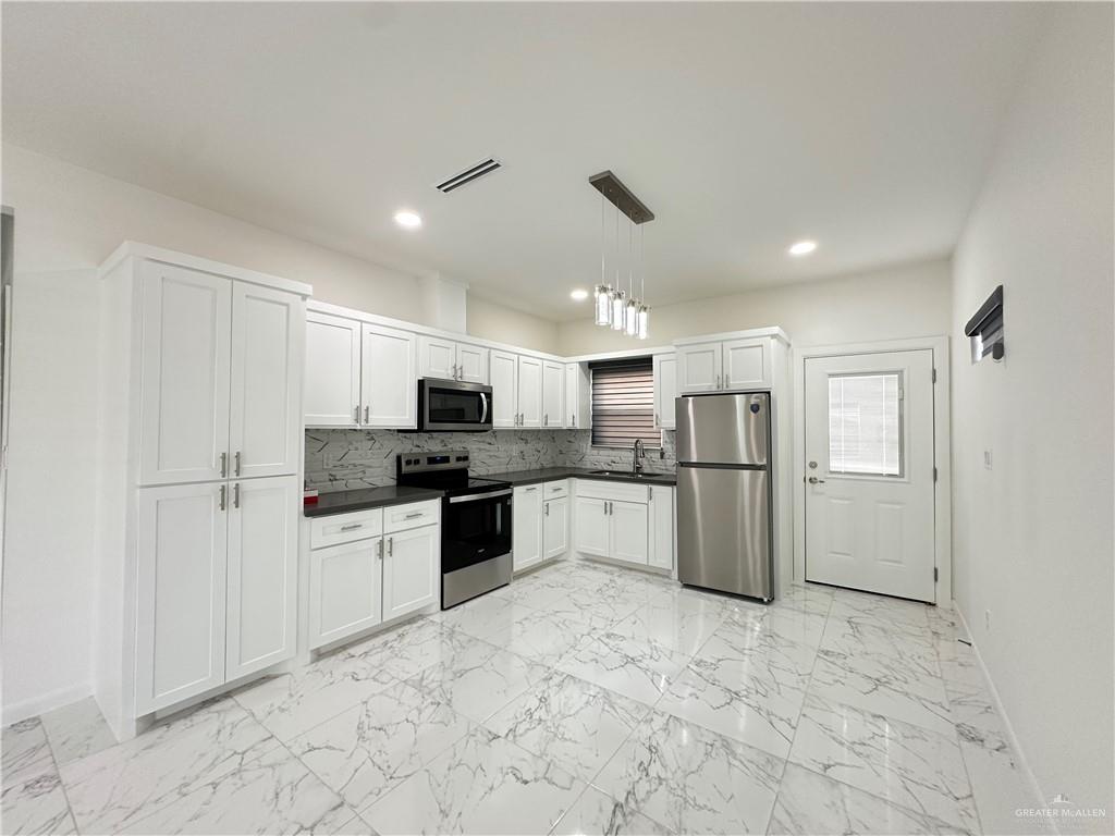 2300 East San Andrea Street, Unit 2 Edinburg, TX 78542 - Photo 3 of 12 a large kitchen with a refrigerator and white cabinets