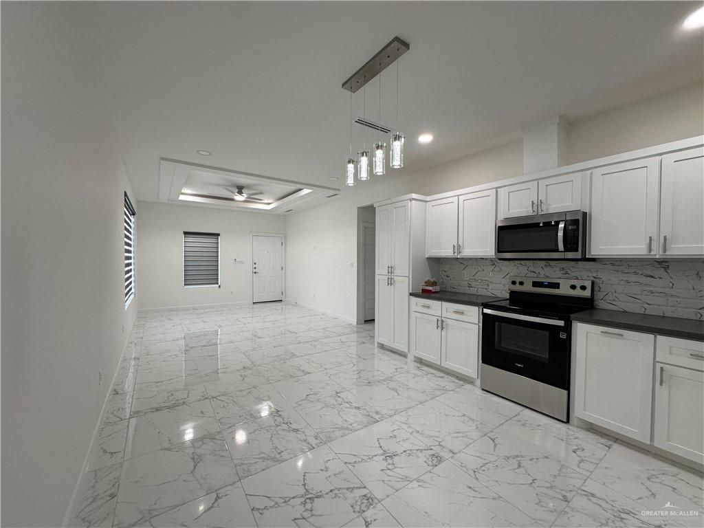 2300 East San Andrea Street, Unit 2 Edinburg, TX 78542 - Photo 7 of 12 a large kitchen with granite countertop a stove a sink a microwave and cabinets