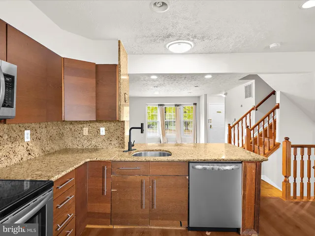 a kitchen with granite countertop a sink a stove and cabinets