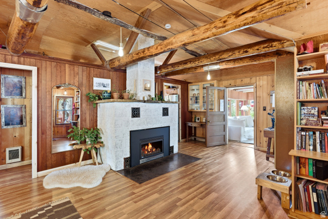 6631 Pine Springs Road Kamas, UT 84036 - Photo 4 of 48 Living area featuring wood walls, wood finished floors, a tiled fireplace, heating unit, and a wooden ceiling with exposed beams
