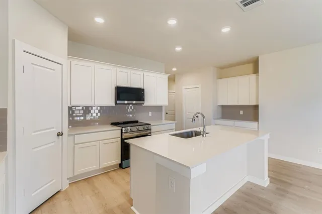a kitchen with a sink a stove a refrigerator and white cabinets