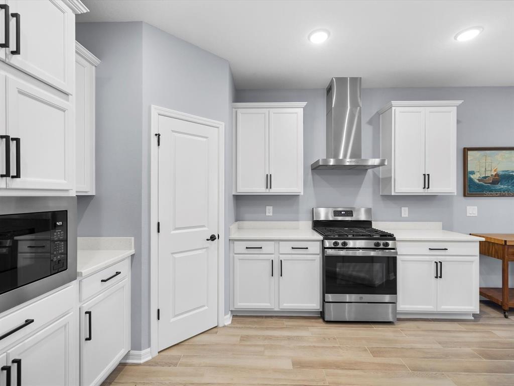 5219 Cappleman Loop Brooksville, FL 34601 - Photo 14 of 60 a kitchen with stainless steel appliances white cabinets a stove a sink and a refrigerator
