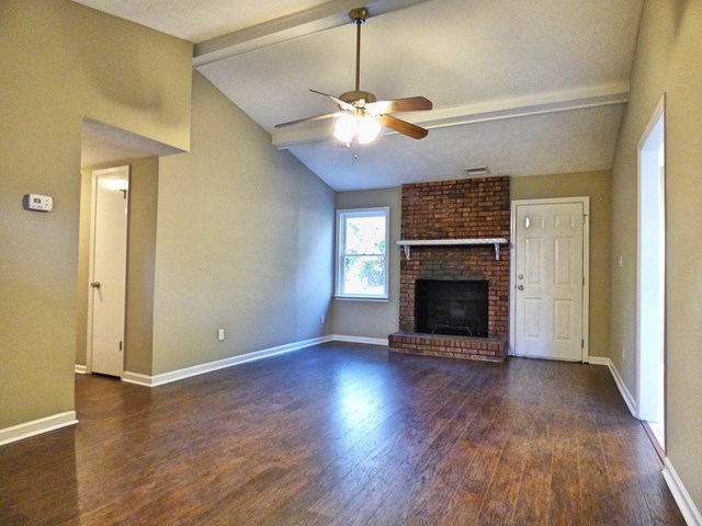 20 Ford Road Phenix City, AL 36869 - Photo 5 of 15 an empty room with wooden floor a chandelier fan and a fireplace