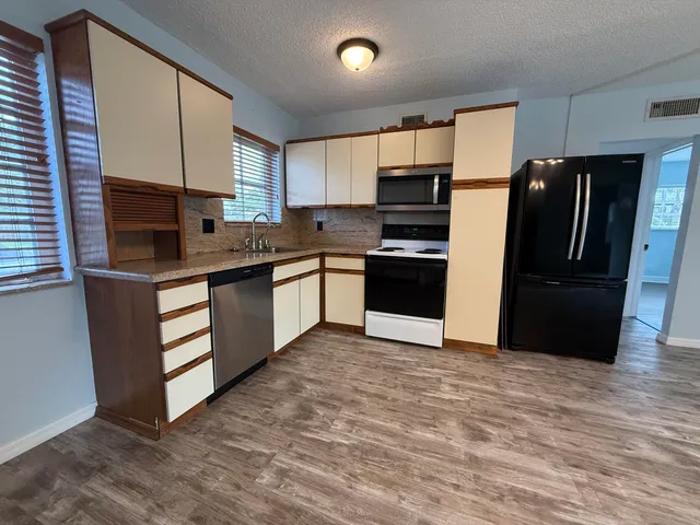 a kitchen with stainless steel appliances granite countertop a stove a refrigerator and a sink