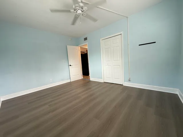 an empty room with wooden floor closet and windows