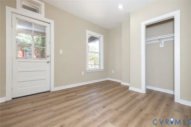 an empty room with wooden floor cabinet and windows