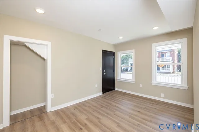 an empty room with wooden floor and windows