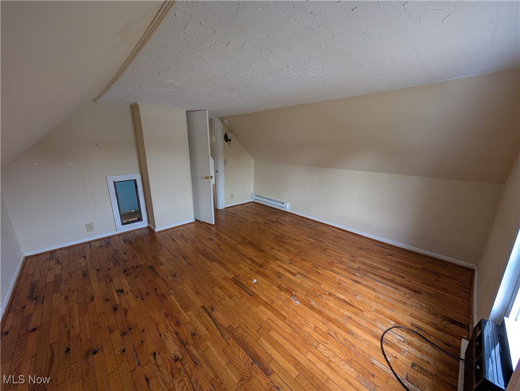 10143 Pleasant Road Pleasant City, OH 43772 - Photo 21 of 32 Bonus room with hardwood / wood-style floors, vaulted ceiling, a textured ceiling, and a baseboard radiator