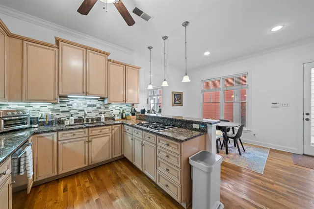 a kitchen with stainless steel appliances granite countertop hardwood floor sink stove dining table and chairs
