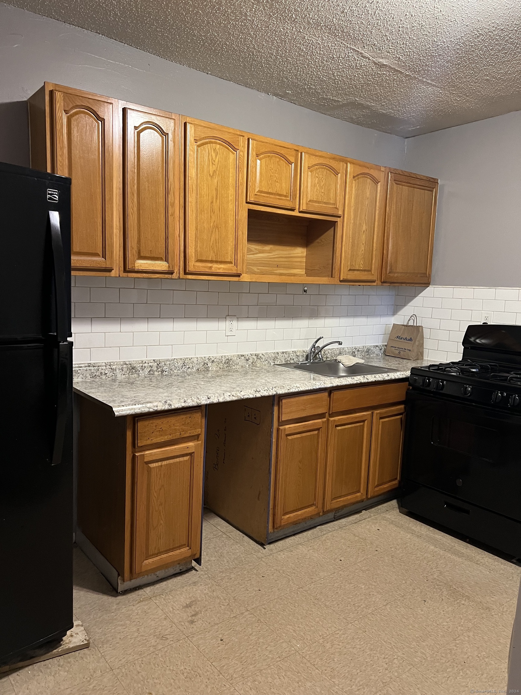 a kitchen with granite countertop a refrigerator and cabinets