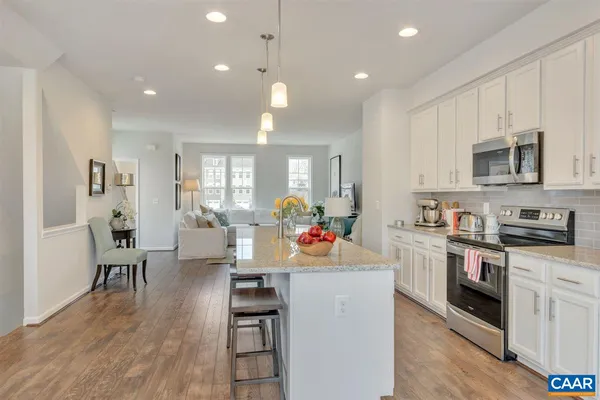 a open kitchen with stainless steel appliances granite countertop a stove top oven a sink dishwasher and white cabinets with wooden floor