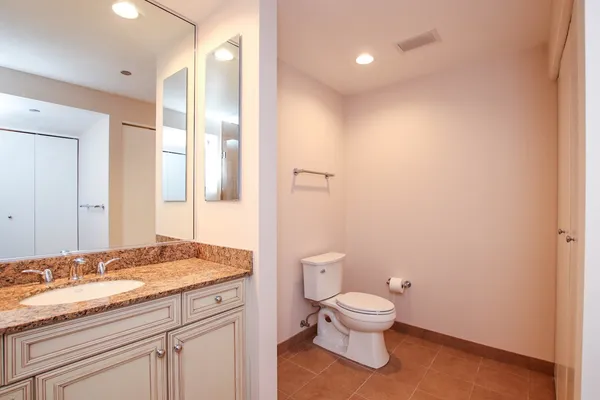a bathroom with a granite countertop toilet a sink and a mirror