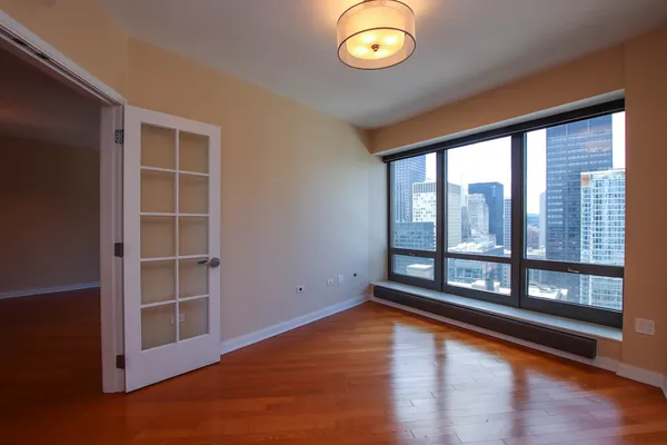 an empty room with wooden floor and windows