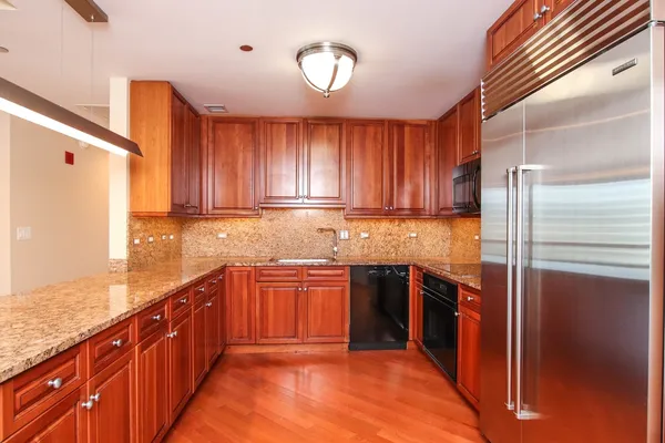a large kitchen with stainless steel appliances granite countertop a refrigerator and a sink