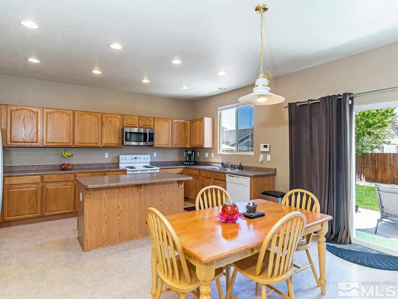 8976 Wynne Street Reno, NV 89506 - Photo 7 of 24 a open kitchen with stainless steel appliances granite countertop a stove top oven a sink a dining table and chairs with wooden floor