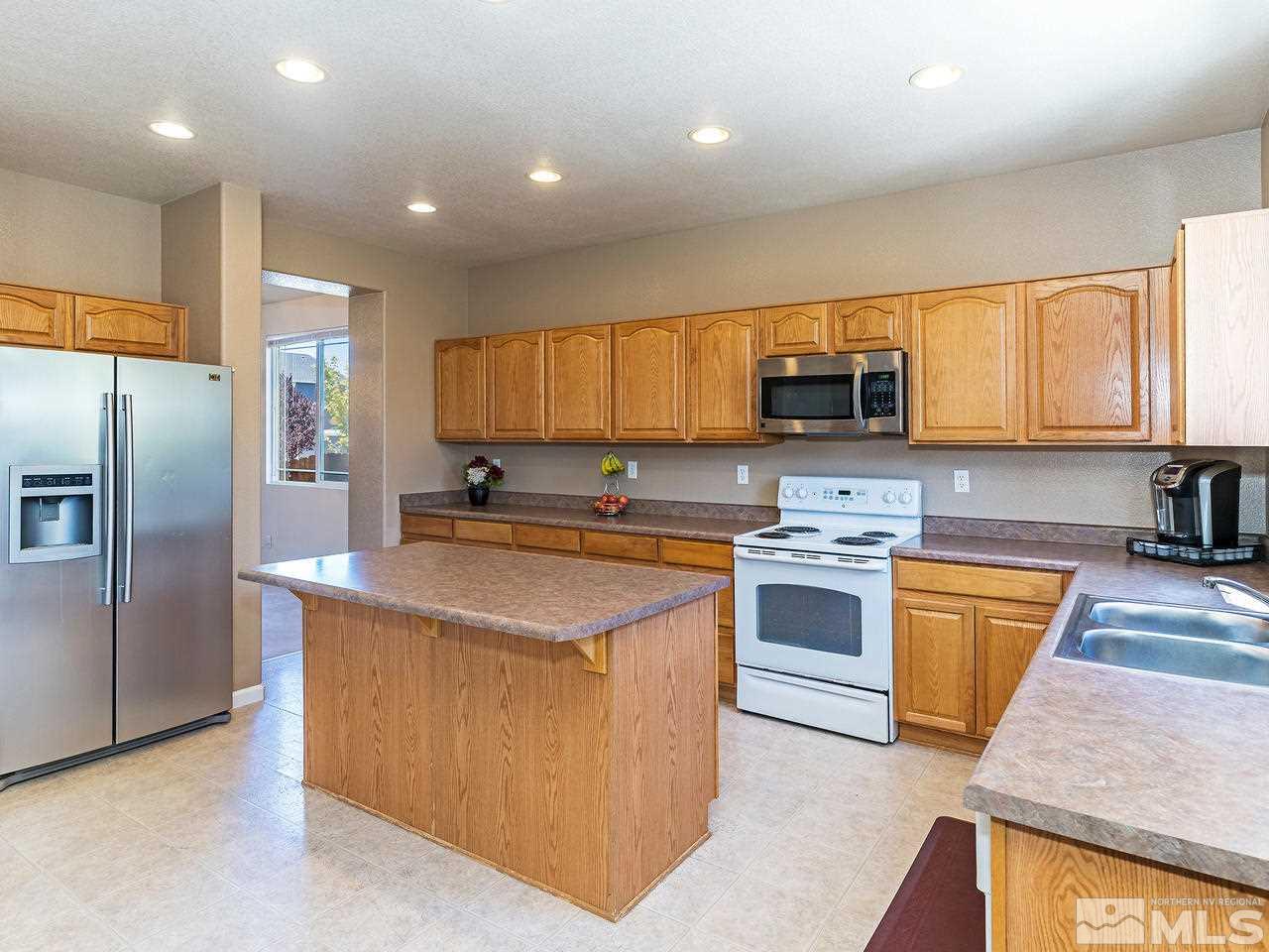 8976 Wynne Street Reno, NV 89506 - Photo 8 of 24 a kitchen with stainless steel appliances granite countertop a stove a sink and a refrigerator