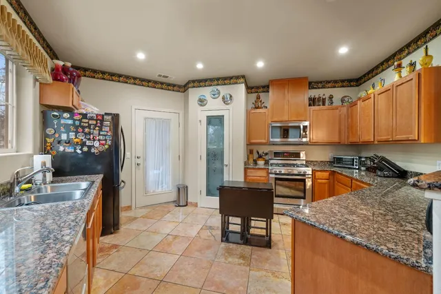 a kitchen with stainless steel appliances granite countertop a refrigerator and a stove top oven