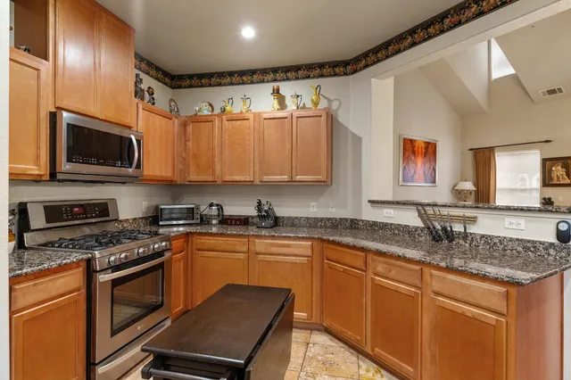 a kitchen with granite countertop a sink stainless steel appliances and cabinets