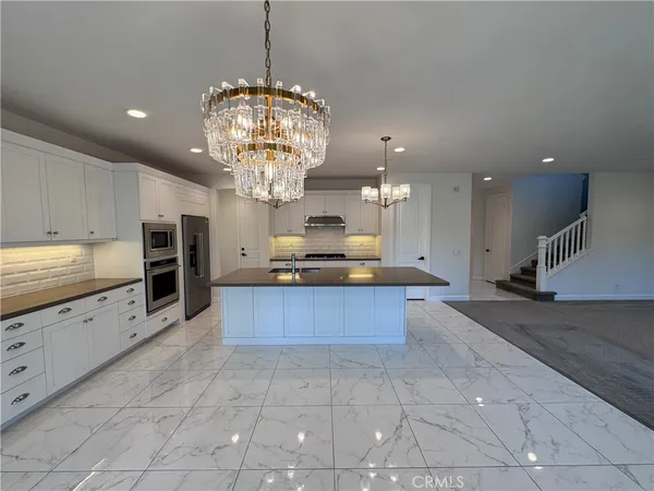a large kitchen with granite countertop a large counter top and stainless steel appliances