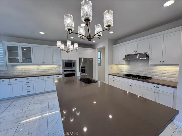 a large kitchen with granite countertop a large island in the center and stainless steel appliances